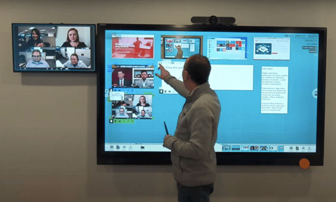 A man in front of ThinkHub docking Teams call to smaller display